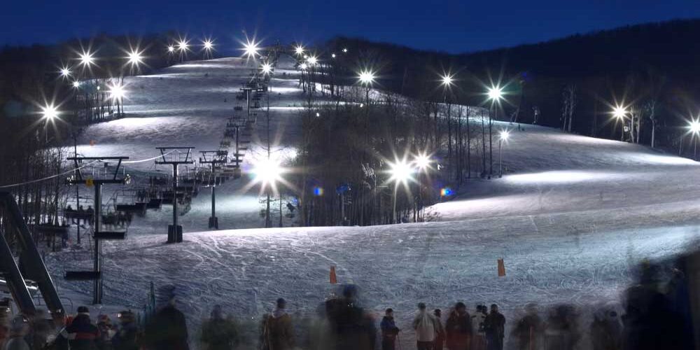 Brighton Ski Resort High mast LED lighting illuminates a ski slope at a resort after dark
