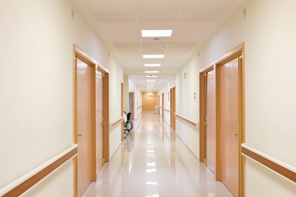 Healthcare Lighting Recessed LED troffers provide warm light to a hospital hallway