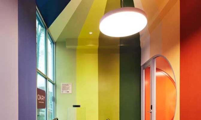 A circular pendant light hanging from the ceiling of a brightly colored store entryway