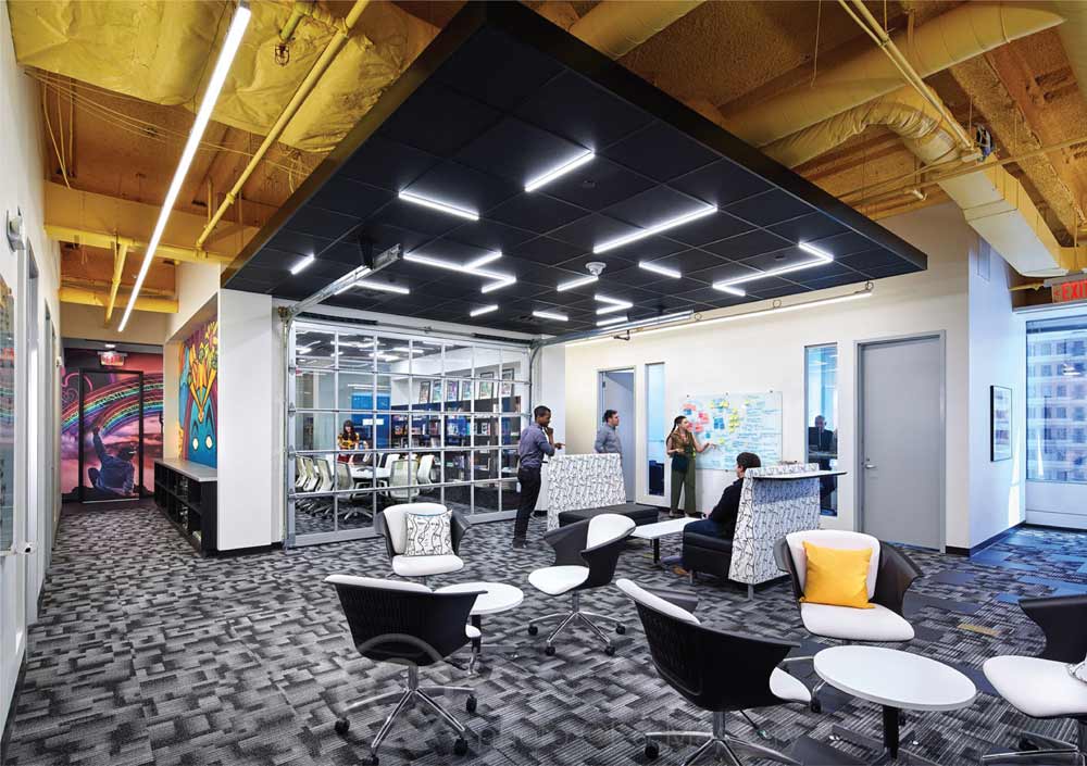 Geometric grid lighting creates visual interest on a black drop ceiling in an office space